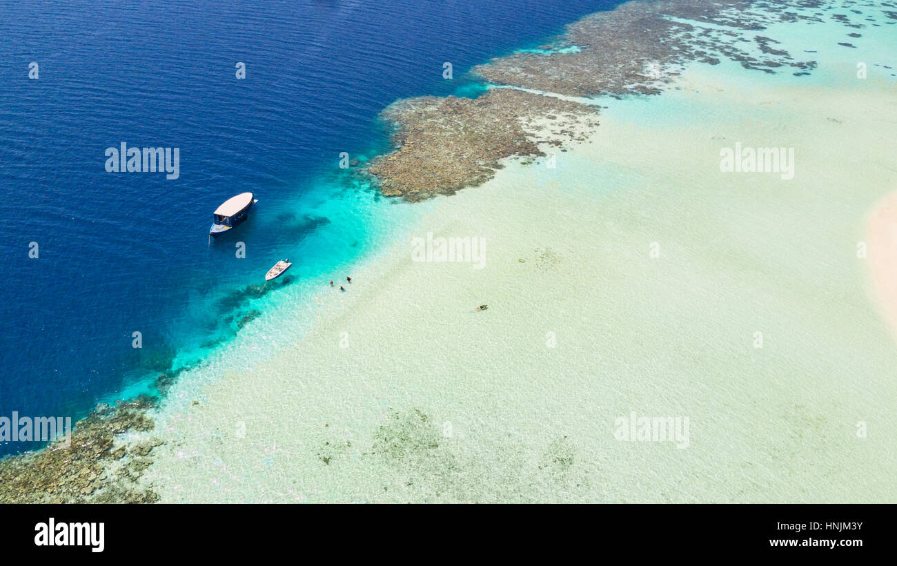 Beautiful coral reef in shallow water with anchoring boats, aerial view. Stock Photo
