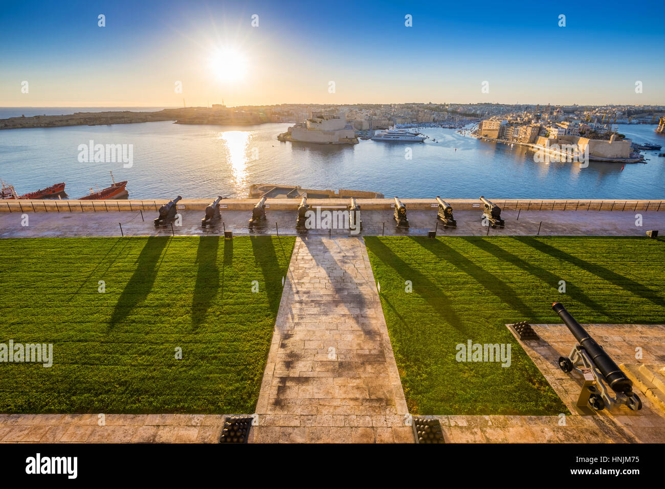 Valletta, Malta - Beautiful sunrise at the famous saluting battery of Valletta with Grand Harbor and Senglea and Brigu at background. Blue sky and sun Stock Photo