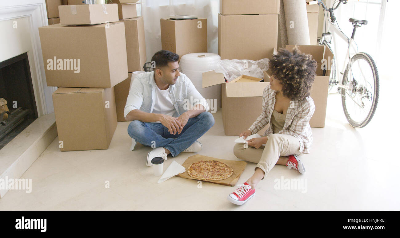 Young Couple Taking A Break From Moving House Sitting On The Floor