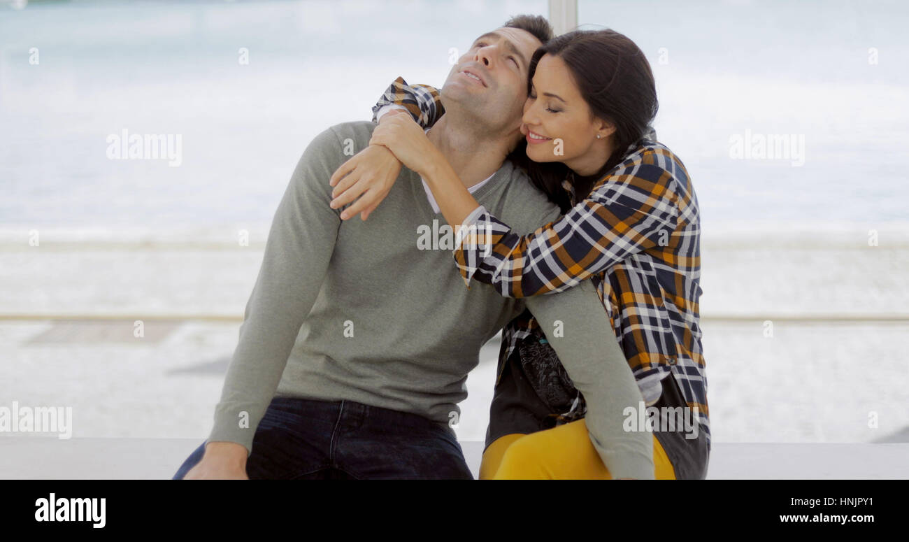 Loving young woman hugging her boyfriend who is relaxing back against ...
