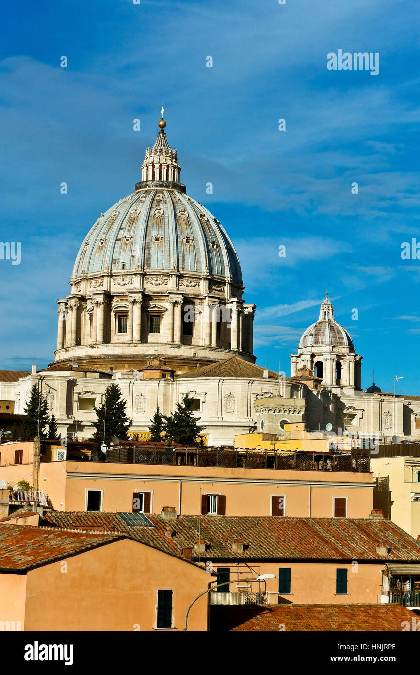 Unusual  view Saint Peter cathedral’s dome seen from the back, dominating the rooftops of adjacent buildings. Cupola Basilica San Pietro. Rome, Italy Stock Photo