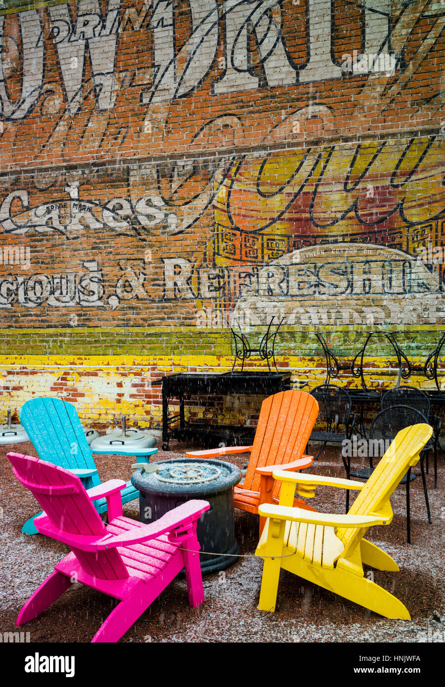 Colorful outdoor chairs & colorful wall mural in snow on patio of Boathouse Cantina restaurant; Salida; Colorado: USA Stock Photo