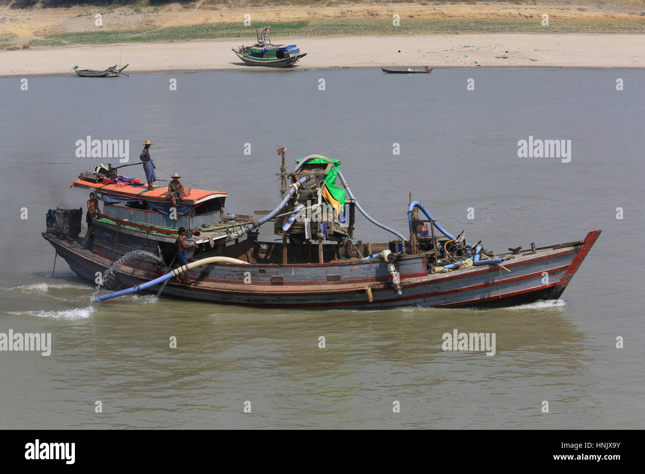 A river dredge boat operating on the Irrawaddy River in Myanmar (Burma). These are often used for gold sluicing or gravel mining. Stock Photo