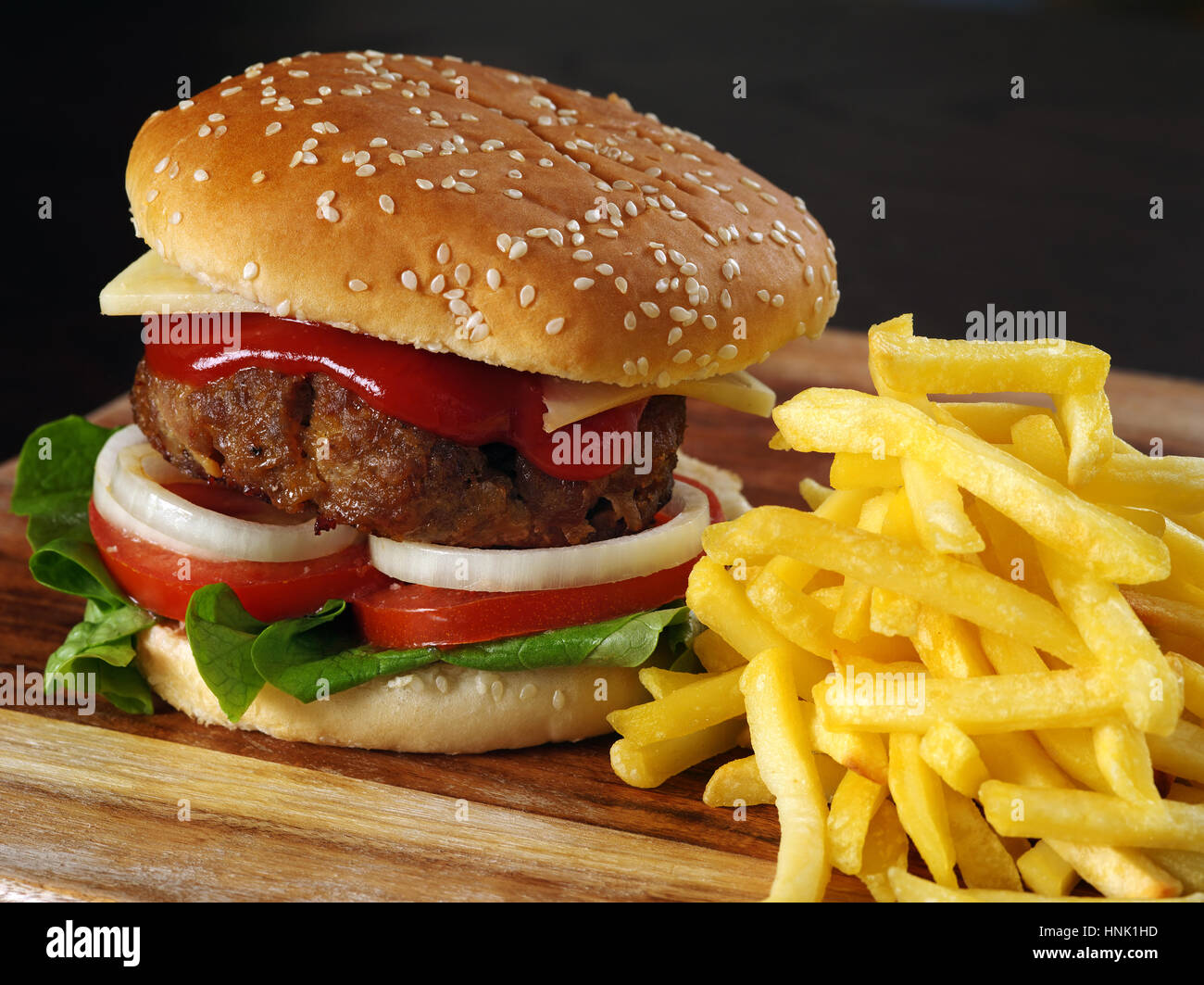 Photo of a hamburger and french fries on a wooden board. Stock Photo