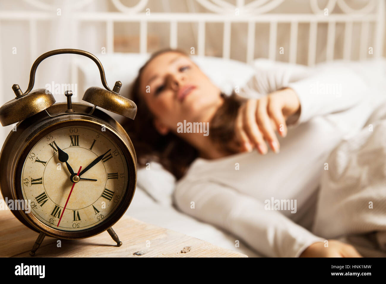 Young woman sleeping in bed beside alarm clock Stock Photo