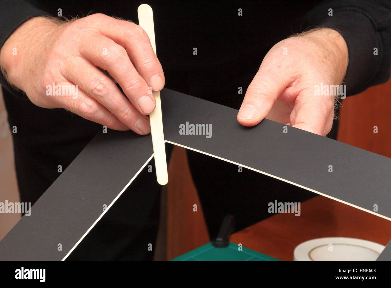 Using a common nail emery board to carefully tidy up small imperfections in the corners of a freshly cut picture mount Stock Photo