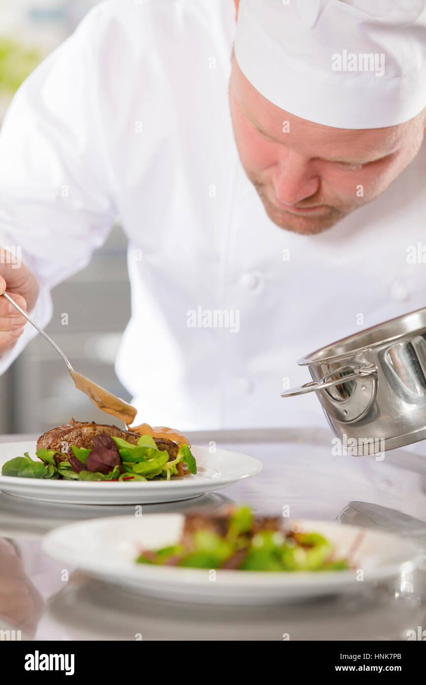 Professional chef prepare meat dish at restaurant Stock Photo