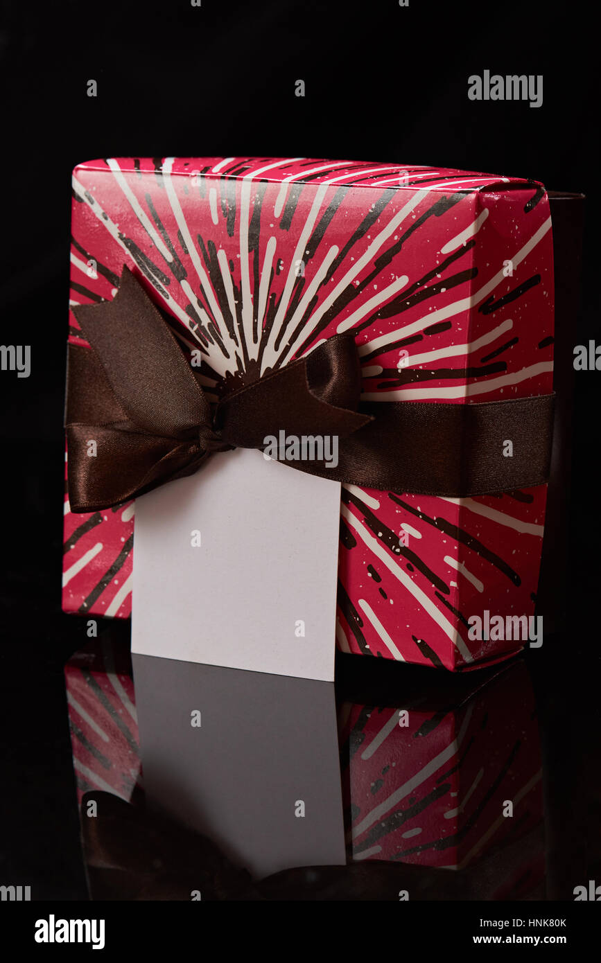 one colorful red gift box with brown ribbon  isolated on black background Stock Photo