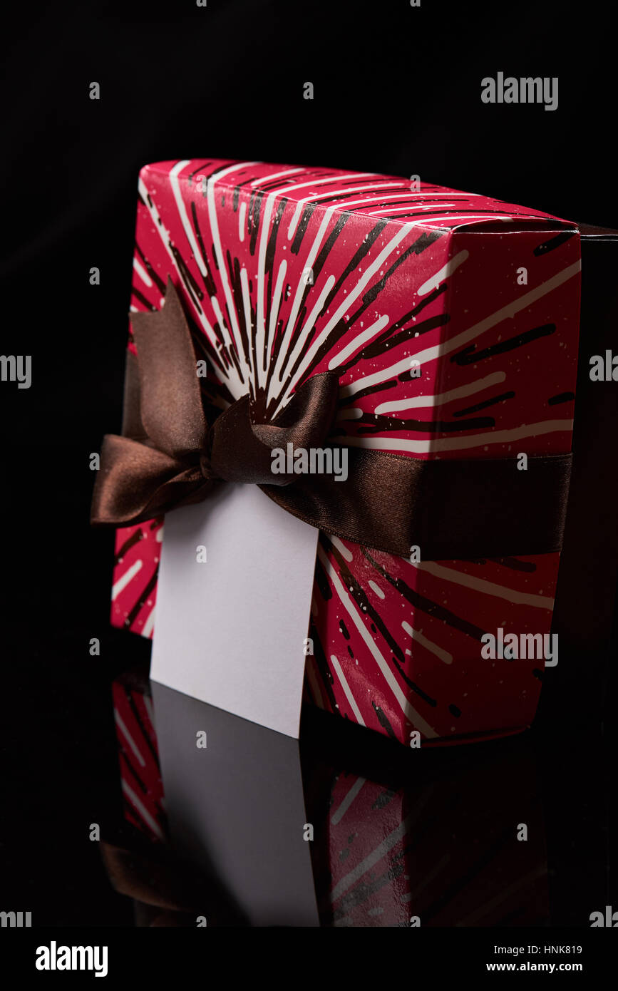 Red present box with brown ribbon and empty space isolated on black background Stock Photo