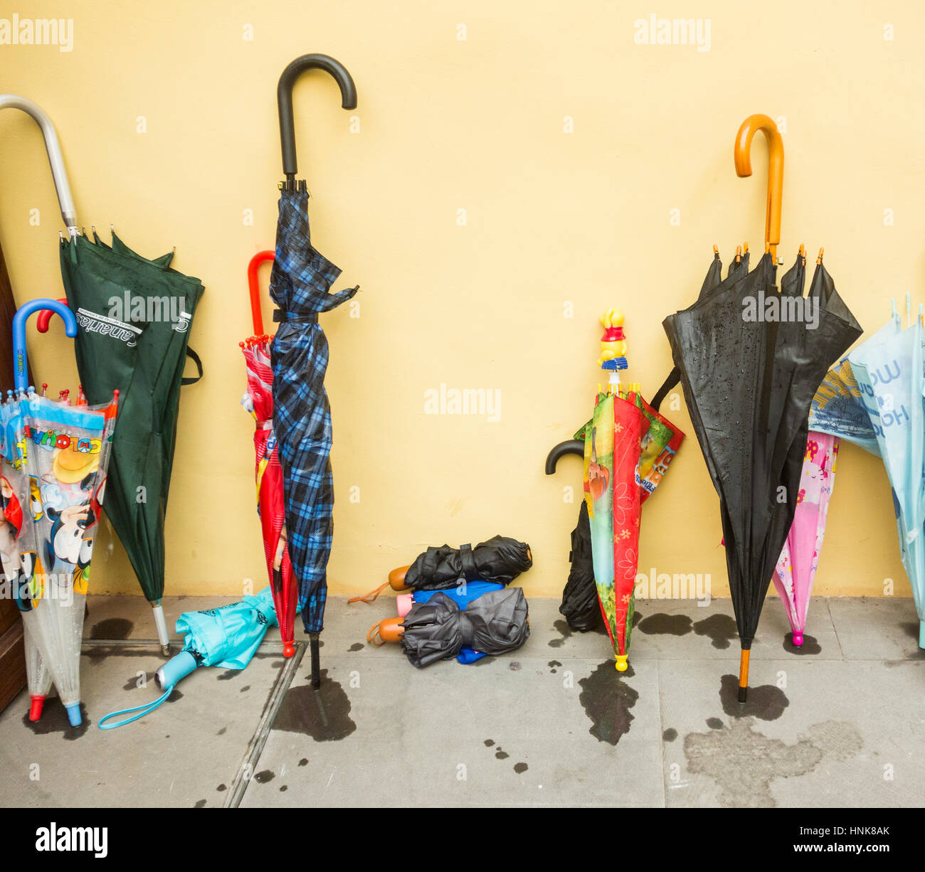 Umbrellas against shop entrance wall Stock Photo