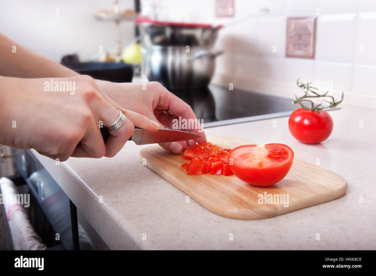 https://c8.alamy.com/comp/HNK8CE/woman-cuts-tomatoes-with-a-knife-on-the-kitchen-table-HNK8CE.jpg