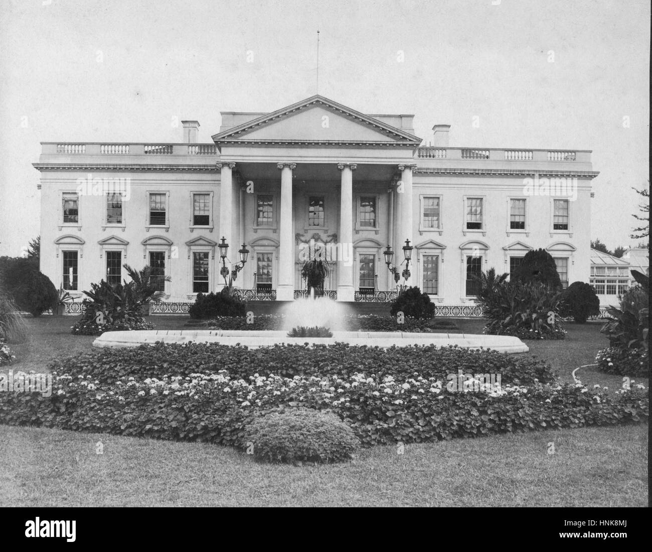 'The White House' c. 1898, at 1600 Pennsylvania Ave. NW.  This is the north side of this American icon, facing Pennsylvania Ave.  Note the Conservatory at the right end of the building. This was replaced by the brand new West Wing in 1902.  No flag on the flag pole. Note the fancy old style of iron fence on the porch. The photo was taken by Mr. J.F. Jarvis, whose studio was at 135 Pennsylvania Ave.  Jarvis had been taking other photos of the White House for decades, both inside and out.   To see my other Places-related vintage images, Search:  Prestor  vintage  places Stock Photo