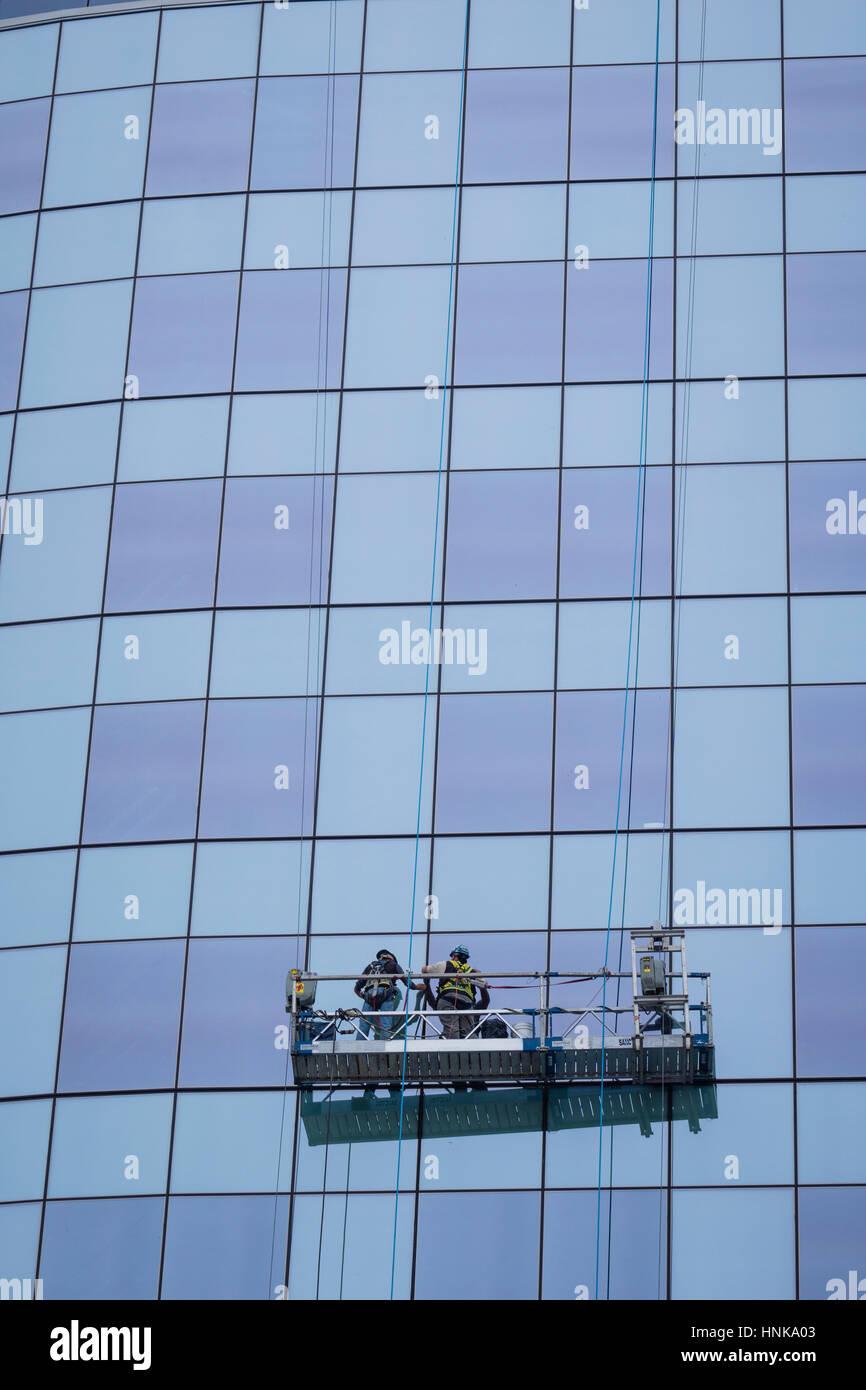Workers On A Swing Stage Repair Windows On A Office Tower