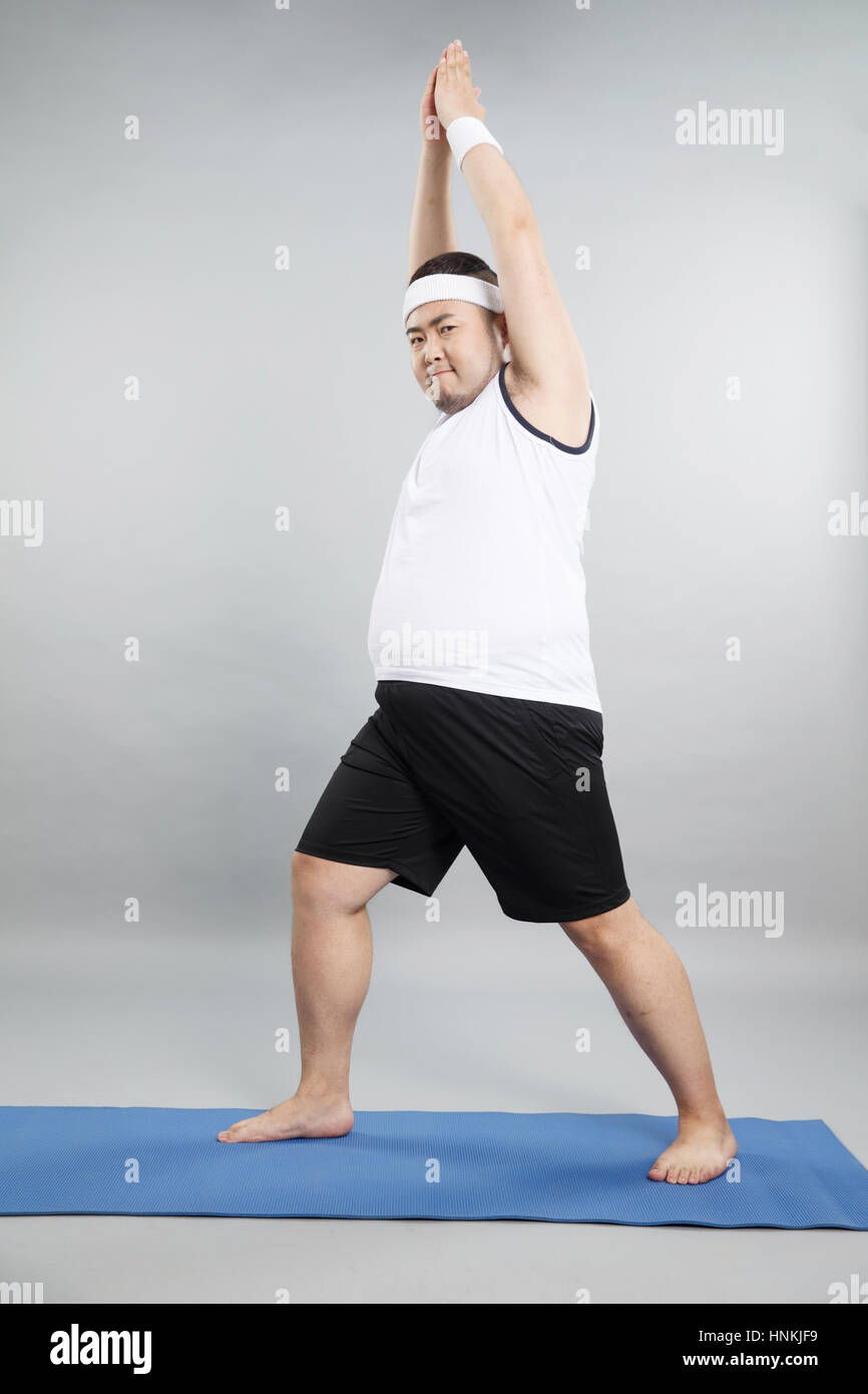 Young fat man doing yoga Stock Photo