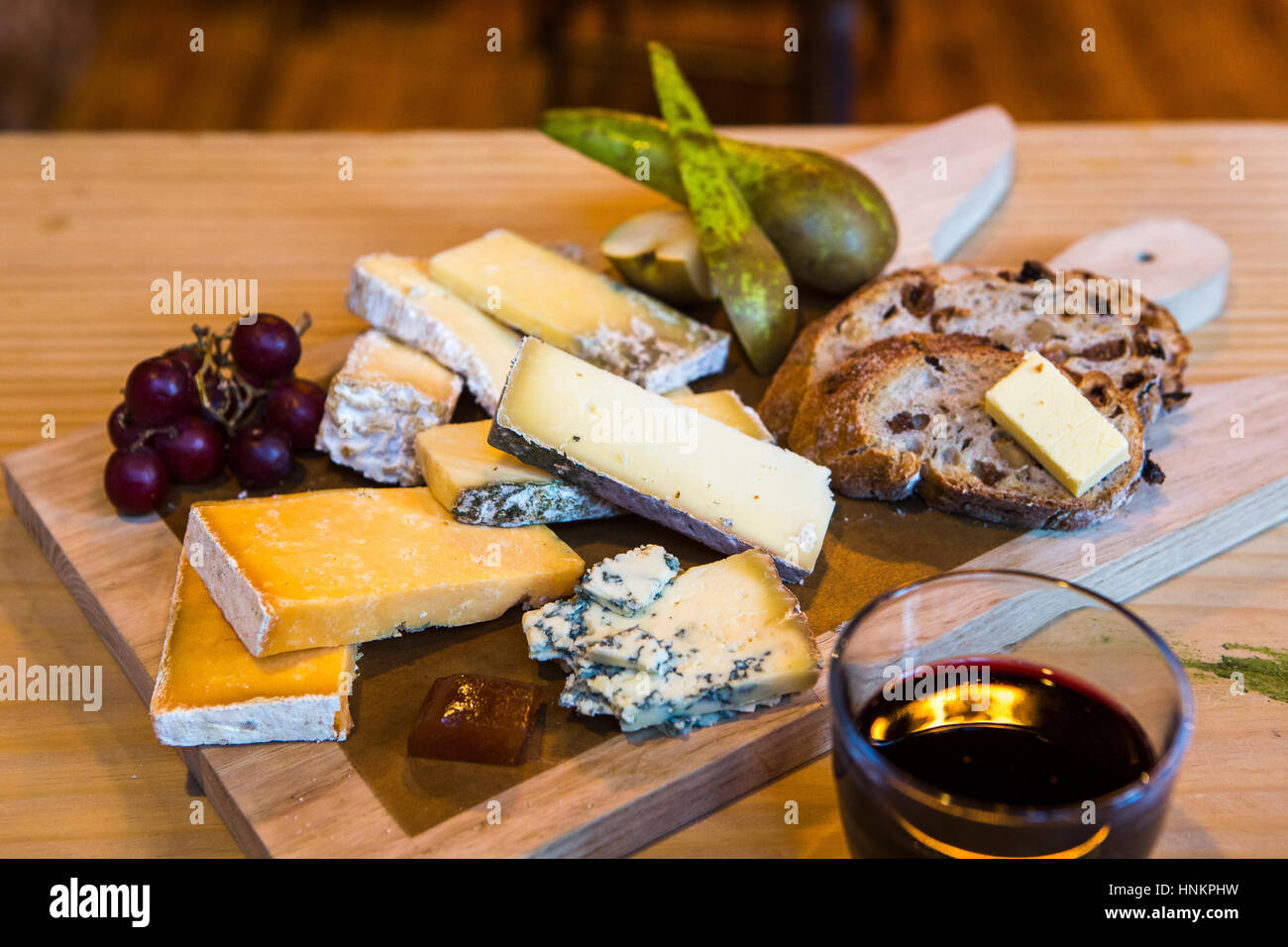 Deli cheese board selection on wooden board with red wine. Stock Photo