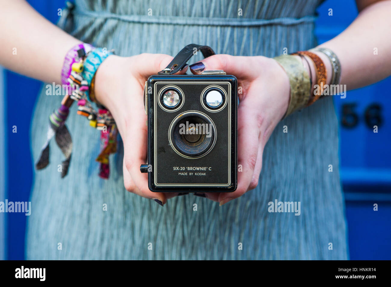 Kodak box brownie camera for film photography, held by caucasion woman with festival wristbands. Stock Photo