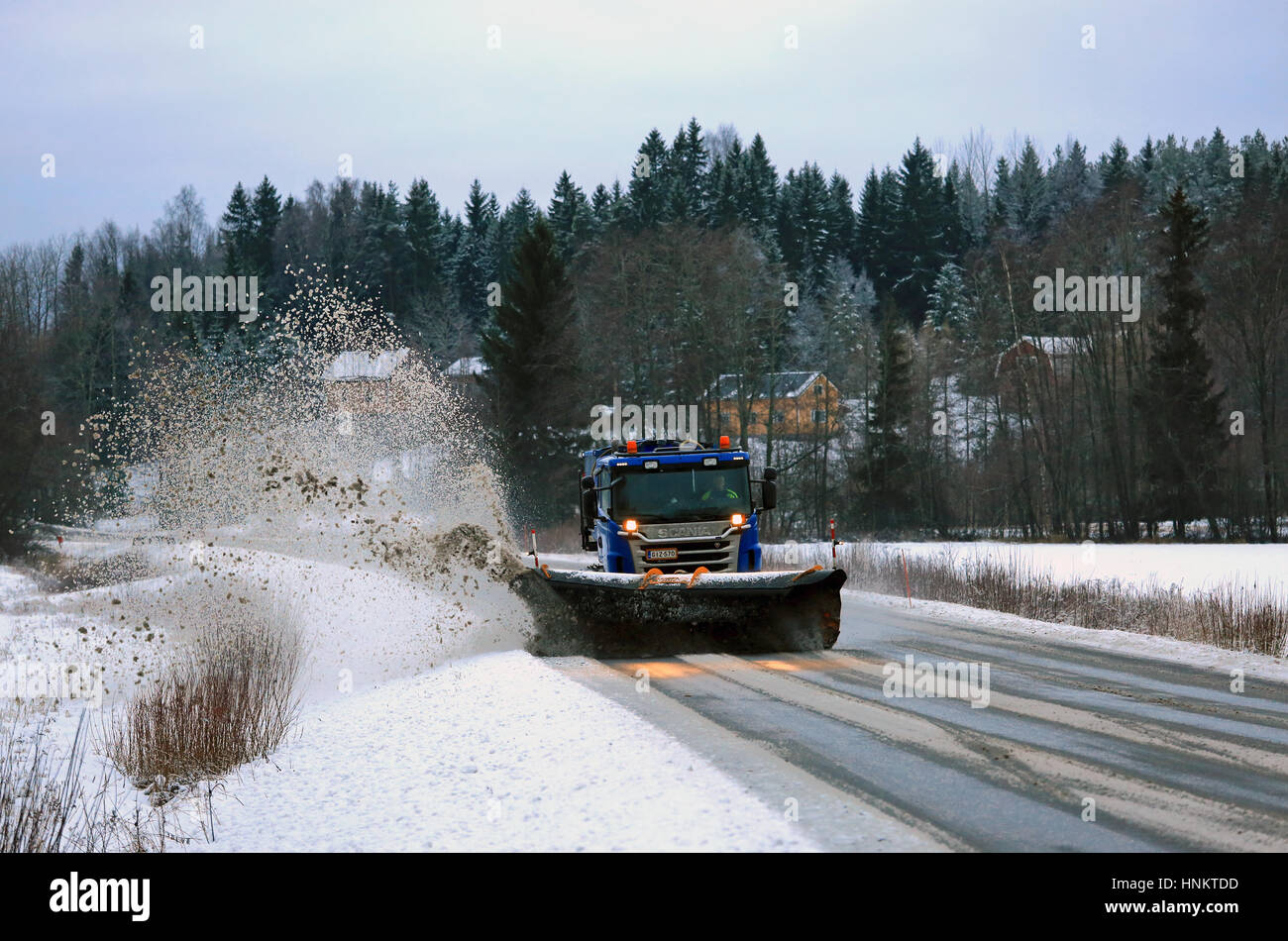 SALO, FINLAND - JANUARY 14: Scania truck equipped with snowplow removes snow and sleet from highway in South of Finland on a cloudy day in winter. Stock Photo