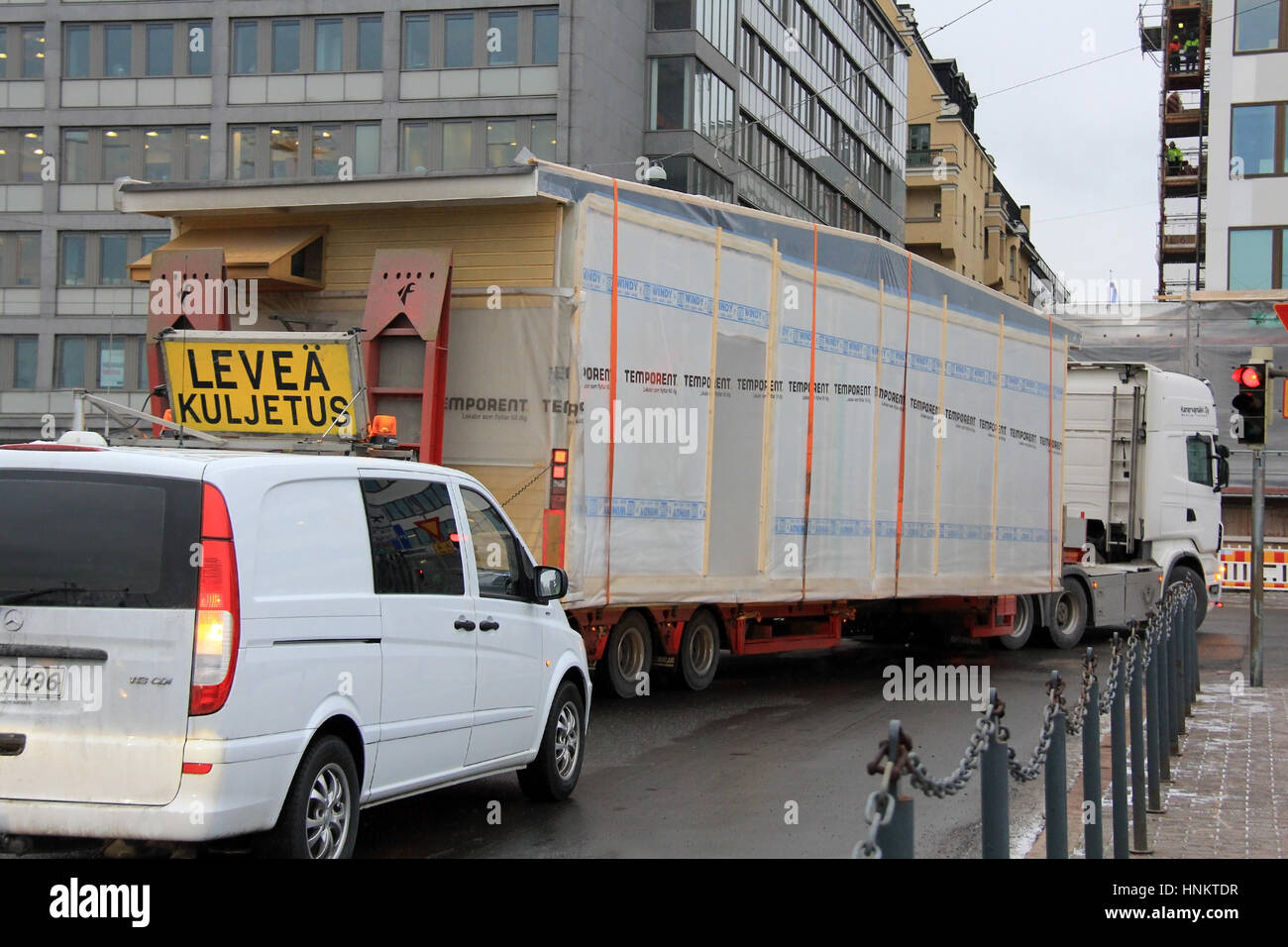 HELSINKI, FINLAND - JANUARY 16, 2017: Escort vehicle assists wide load oversize transport of Temporent prefabricated house module in narrow turn right Stock Photo