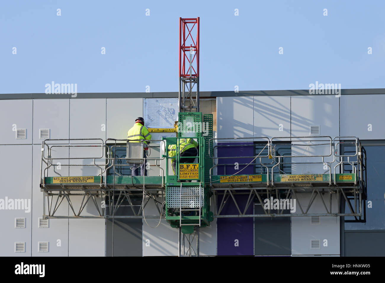 A mast climbing work platform supplied by bft in use at London Heathrow Airport. Fitting cladding to a new Premier Inn Stock Photo