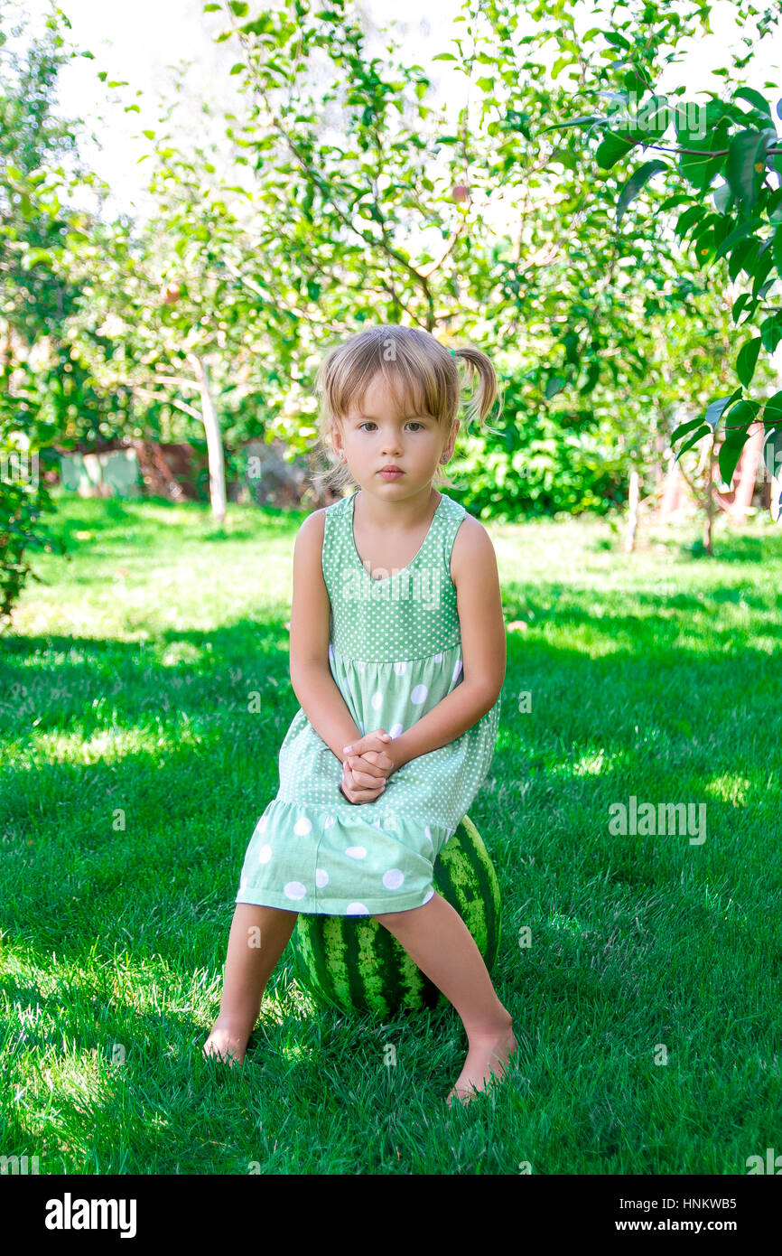 Little girl in green dress sitting on the watermelon in the park, outdoor.  Summer Stock Photo - Alamy
