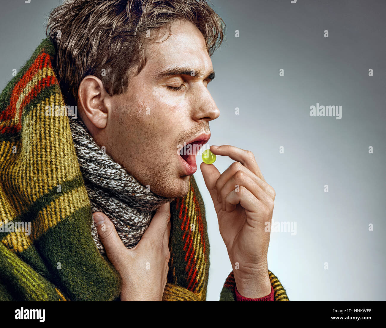 Man With Open Mouth Take Pill For Throat P O Of Sick Man Wrapped In Blanket On Grey Background Man With Open Mouth Take Pill For Throat P O Of Sick Man Wrapped In Blanket On Grey Background