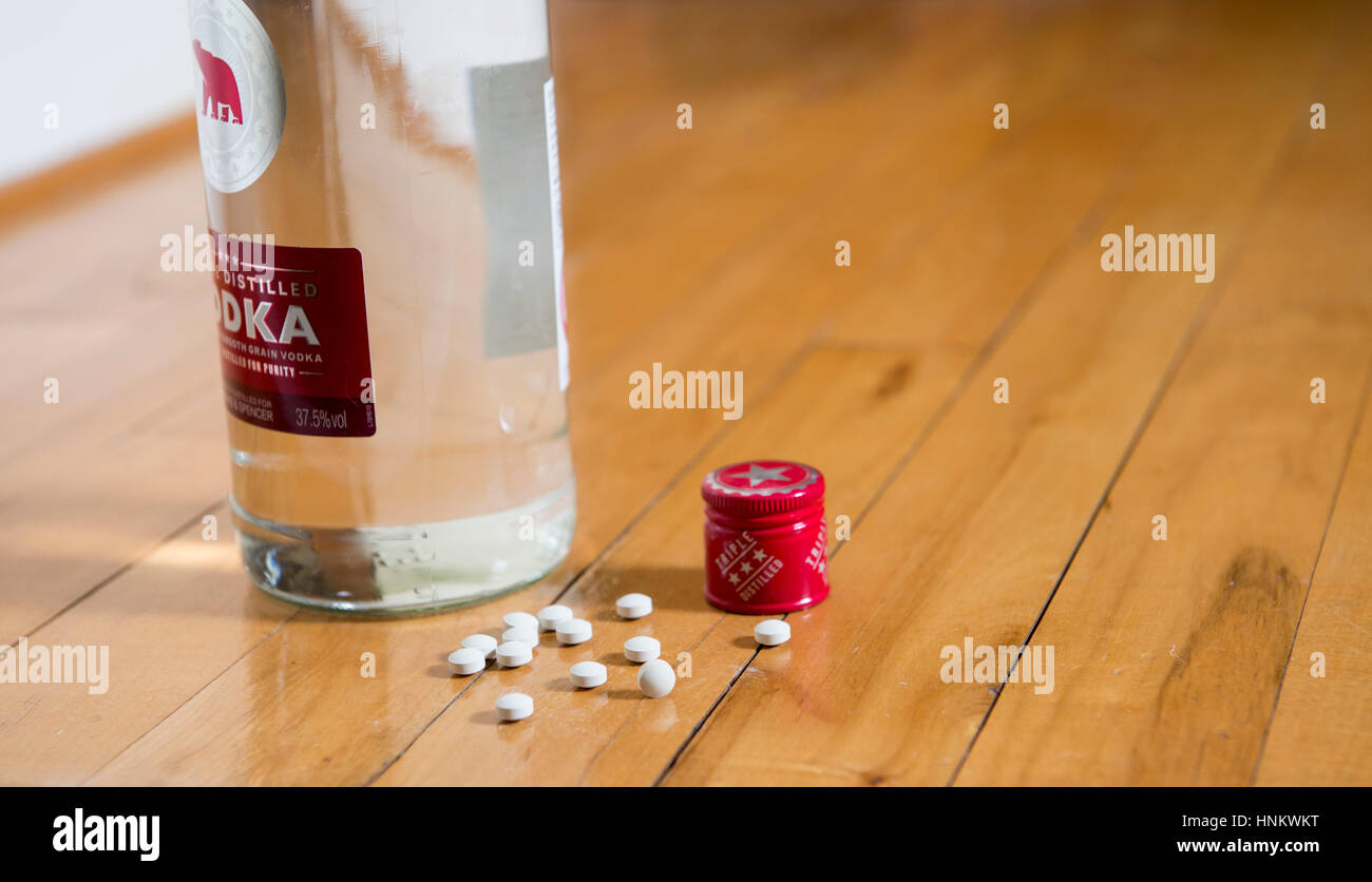 Bottle of Vodka and tablets on floor for depression self medicating illness Stock Photo