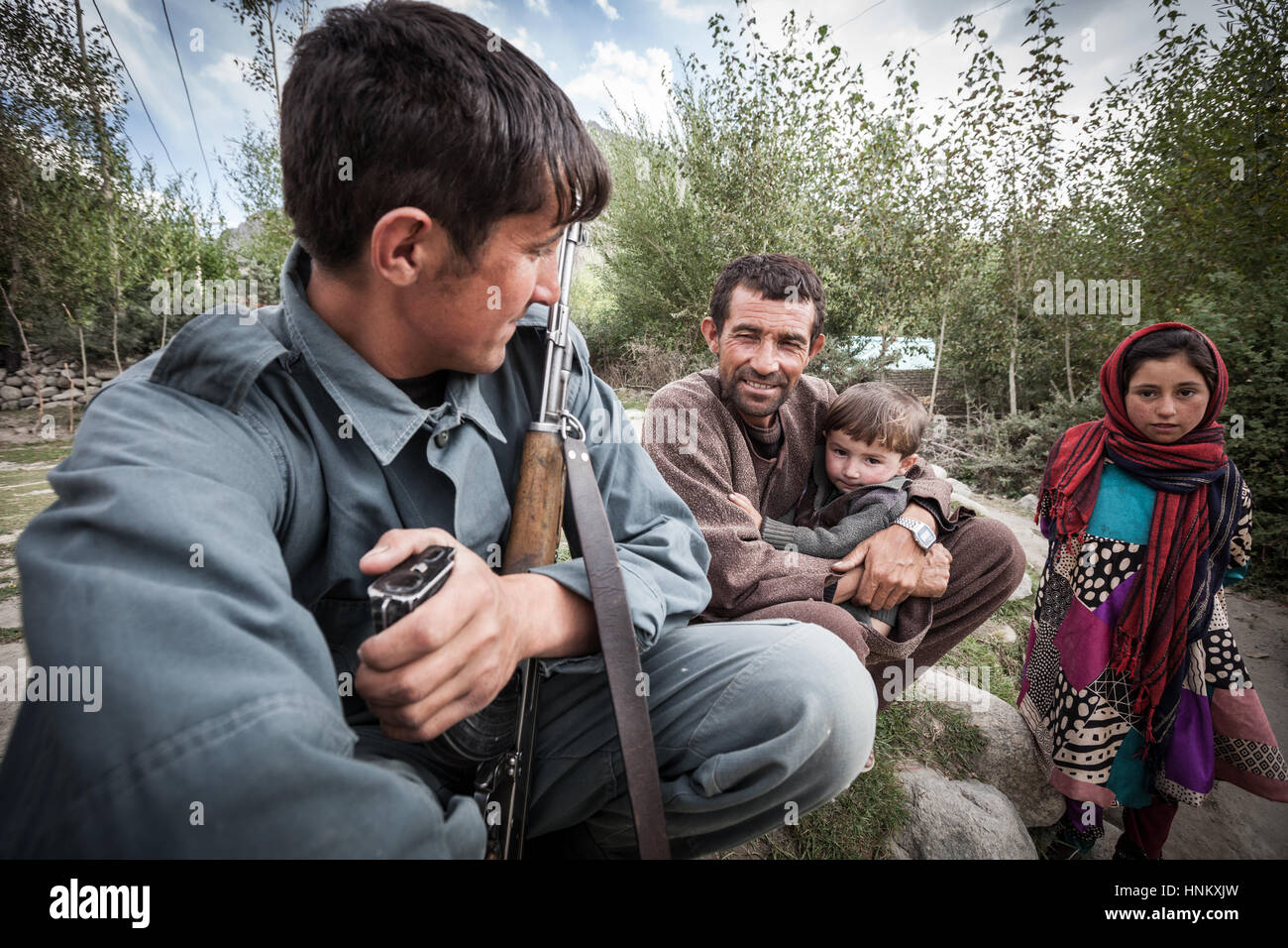 Afghanistan, Wakhan corridor, a family with traditional clothes, outside of their house, boy with machine gun. Stock Photo