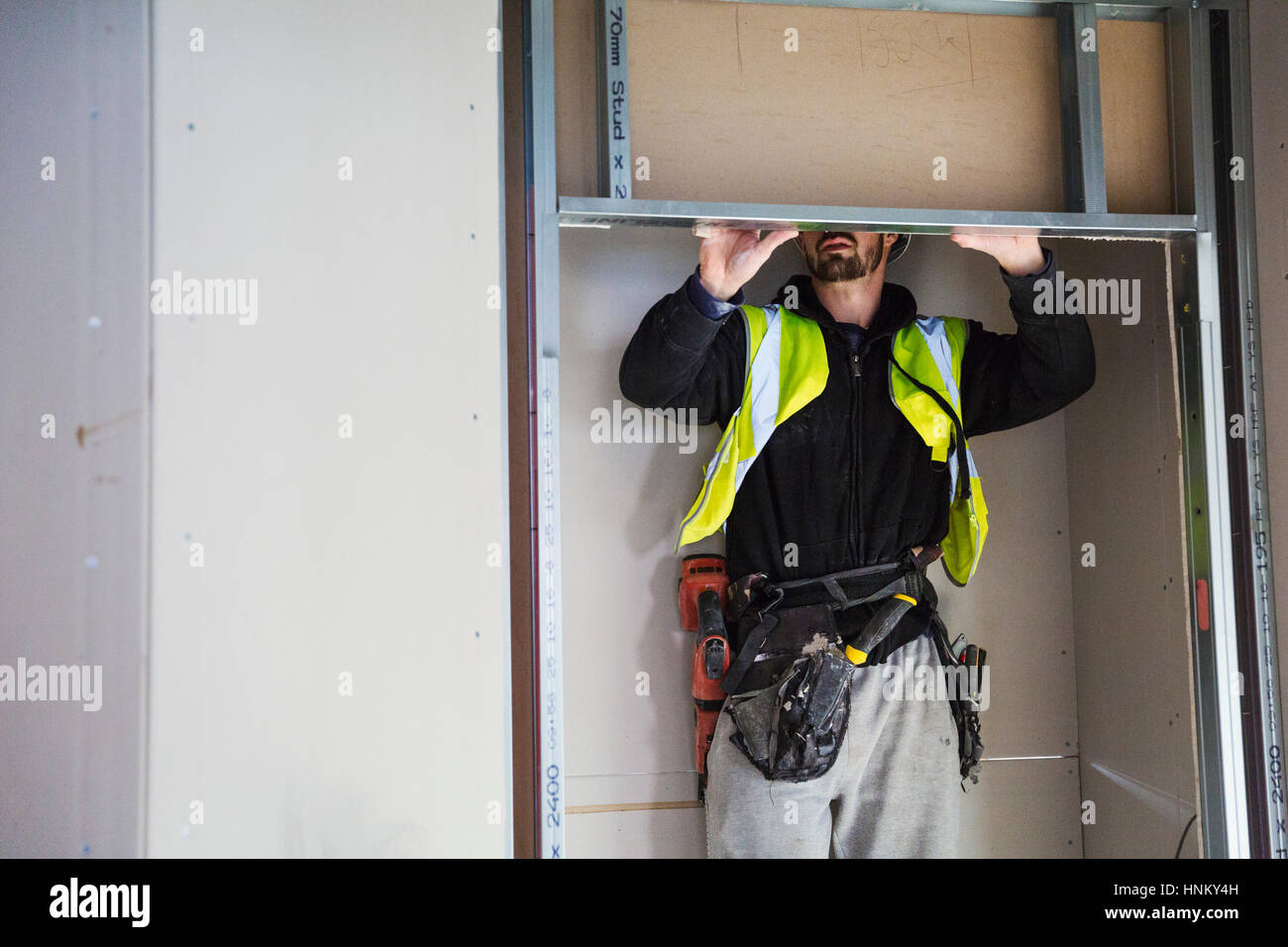 A carpenter in a small space fitting a shelf into a wall cupboard Stock