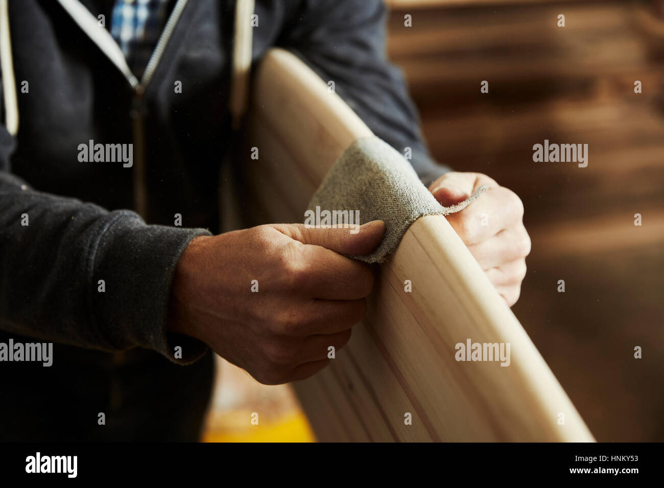 Man standing in a sanding the rounded edge of a wooden