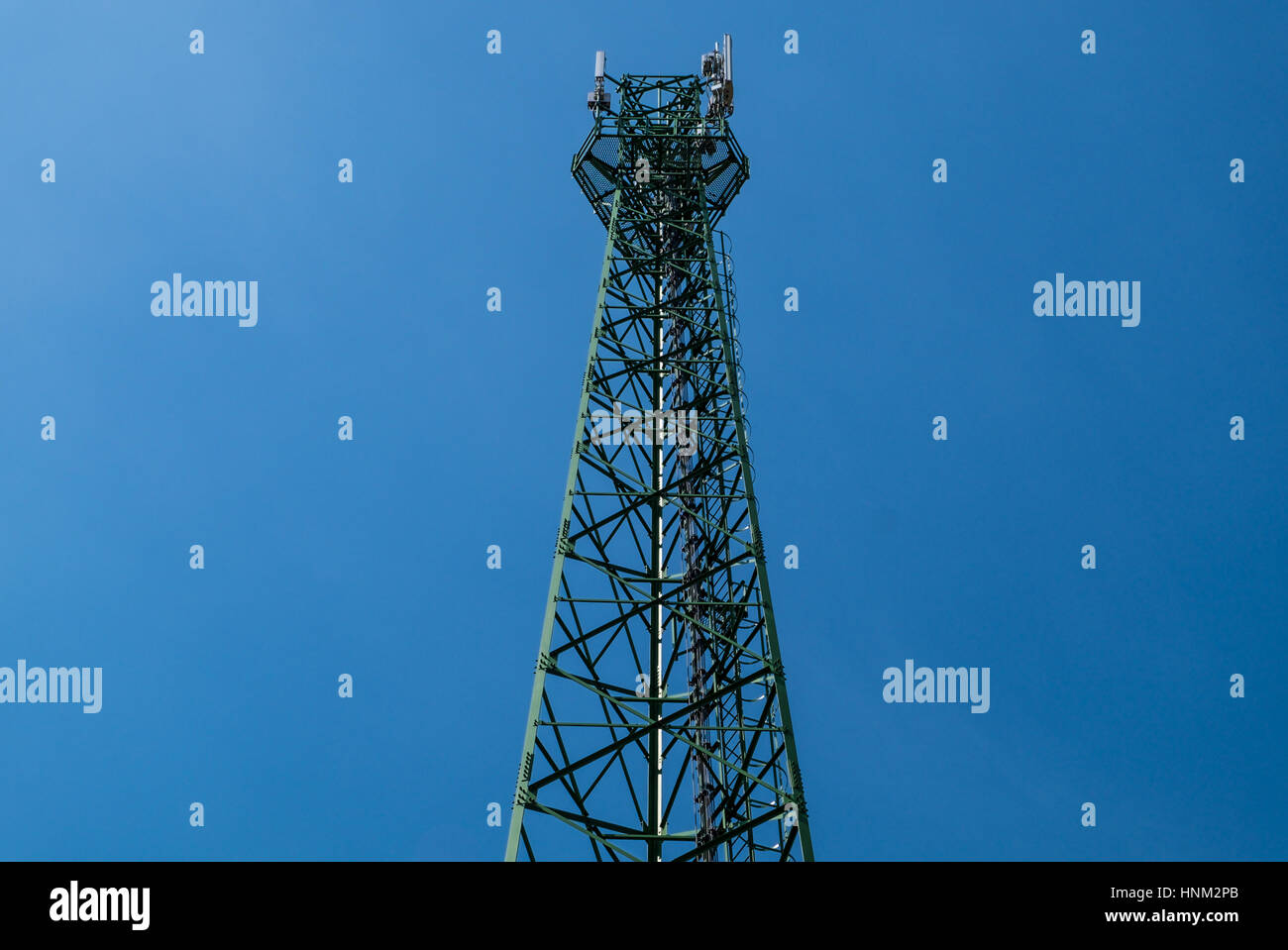 Green antenna tower with gradient blue sky background. Stock Photo