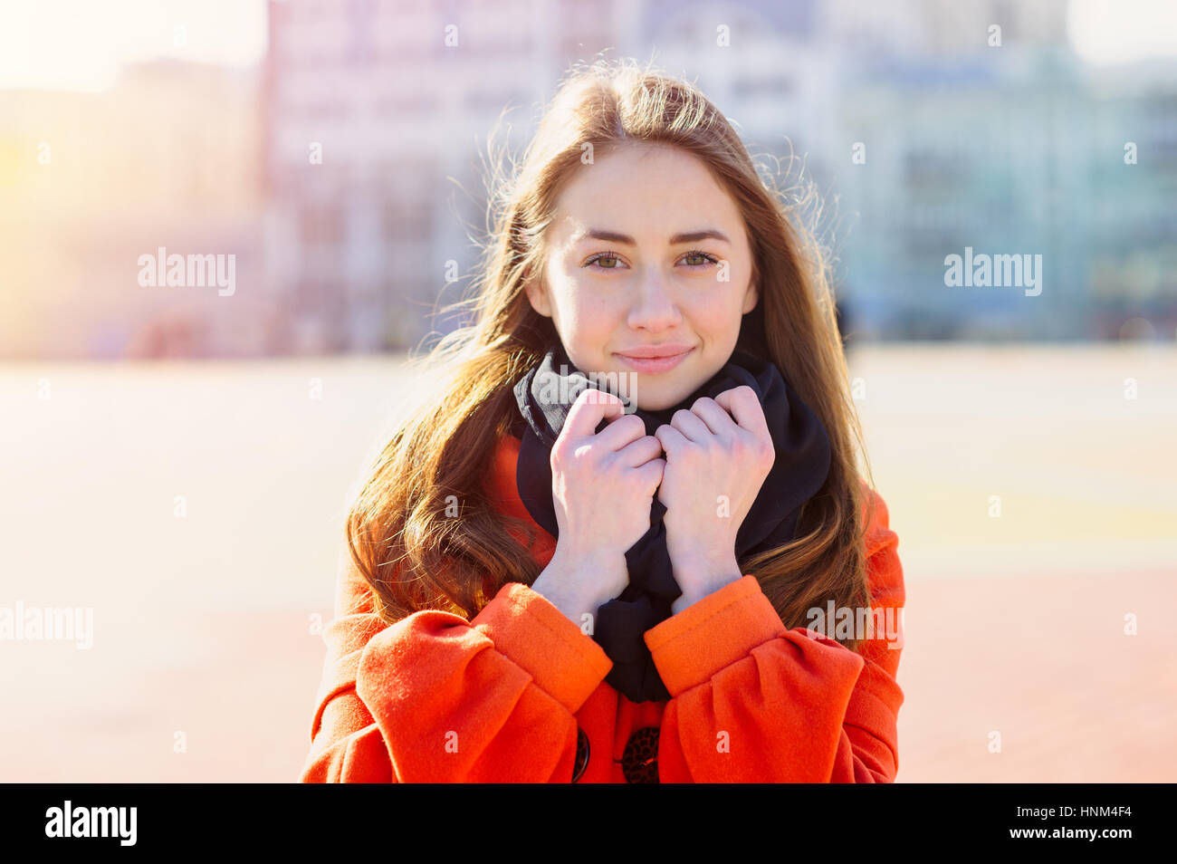 Beautiful young woman in orange coat walking in the city Stock Photo