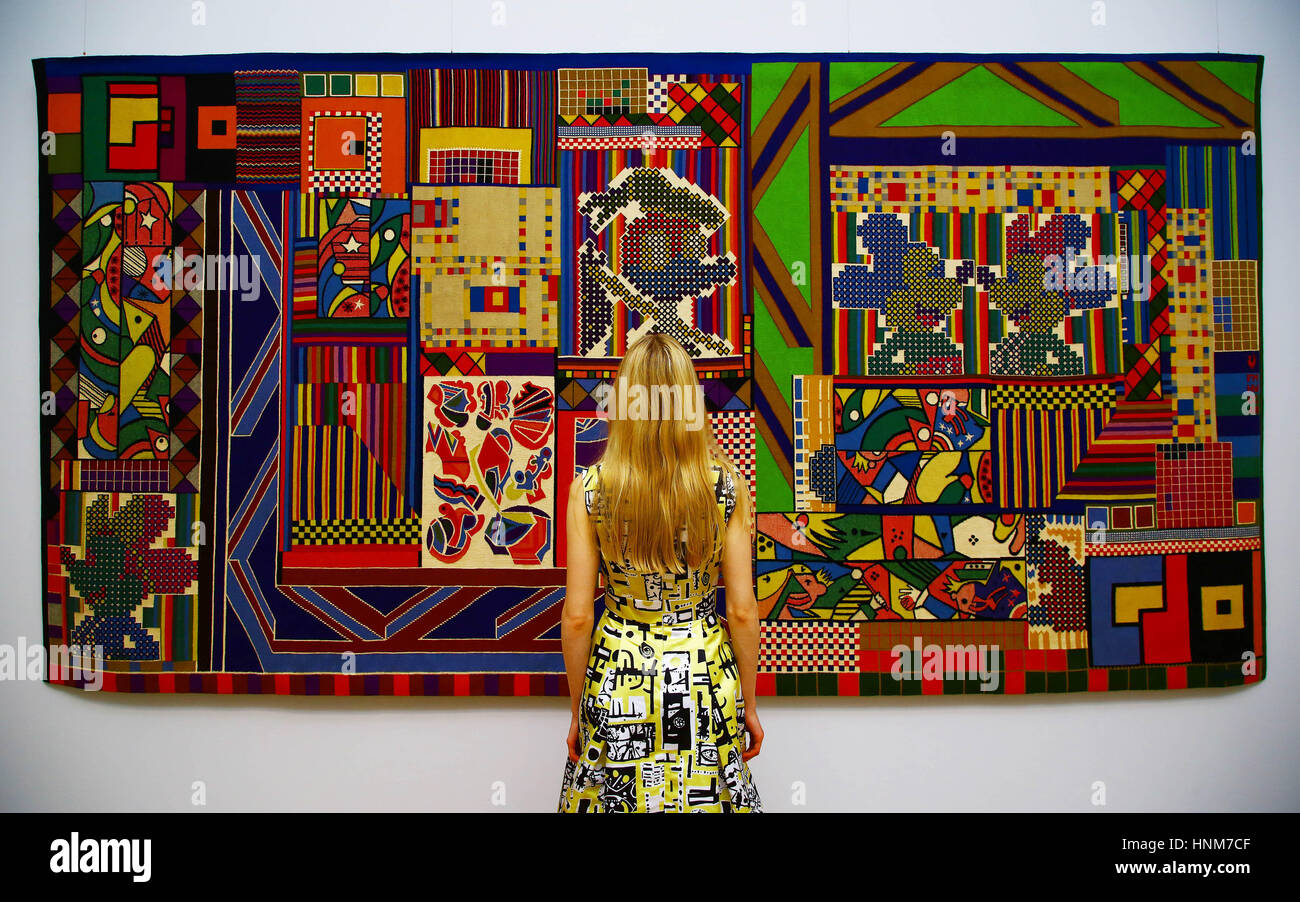 Hannah Vitos wears a modern replica of a 1953 Horrockses dress featuring fabric designed by Eduardo Paolozzi as she stands in front of The Whitworth Tapestry (1967) at the press view of a major retrospective of Paolozzi's work, at the Whitechapel Gallery in east London which opens tomorrow 16 February. Stock Photo