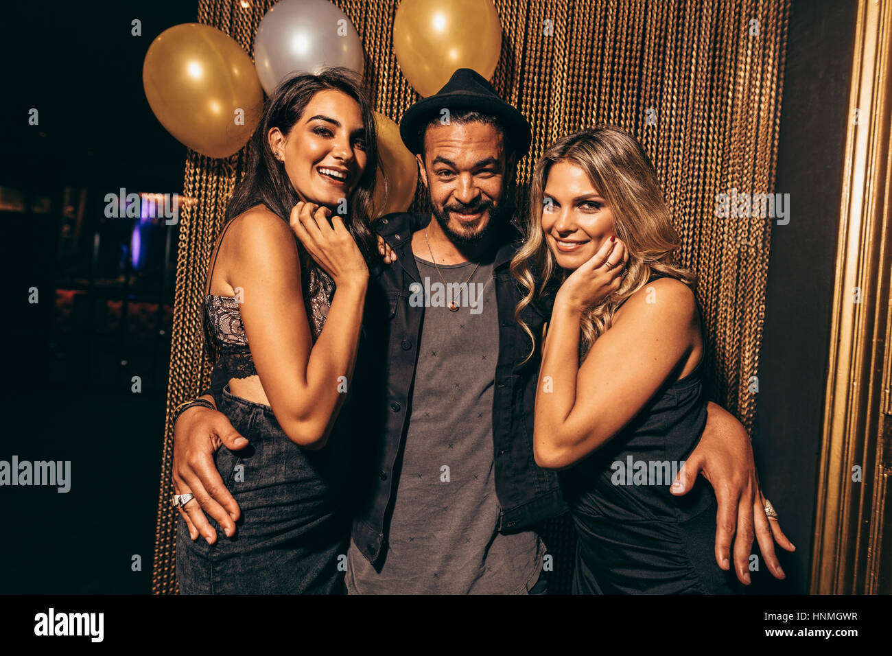 Portrait of handsome young man with female friends at nightclub. Young people partying at pub. Stock Photo