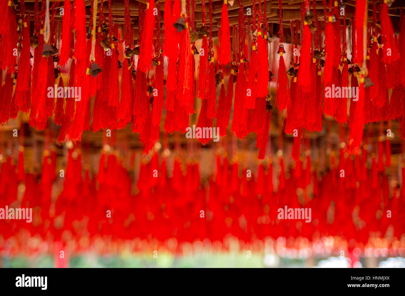 Red decorative threads hanging from a wooden structure at a Buddhist ...