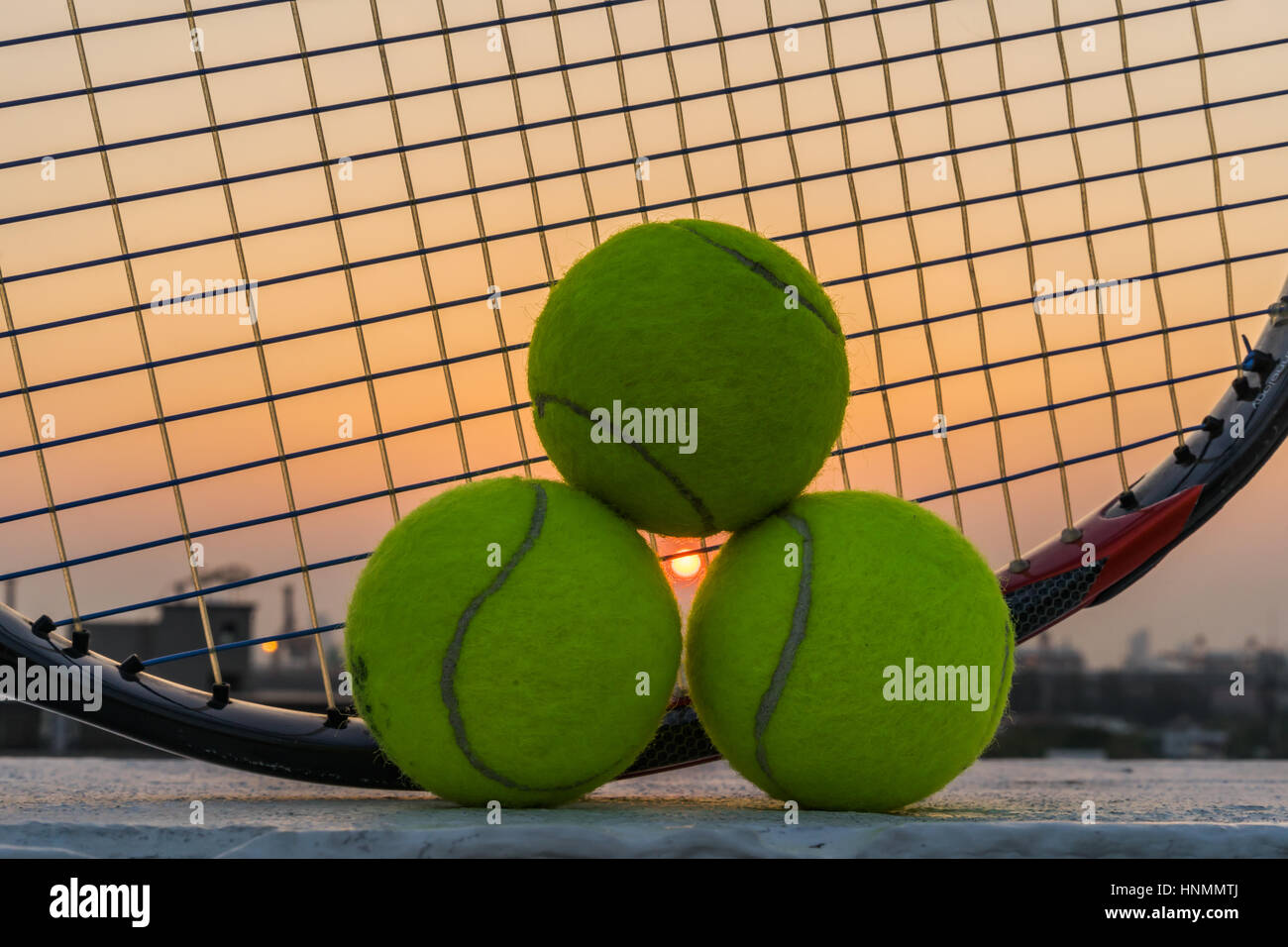 Tennis racket with sunset and tennis balls. Stock Photo