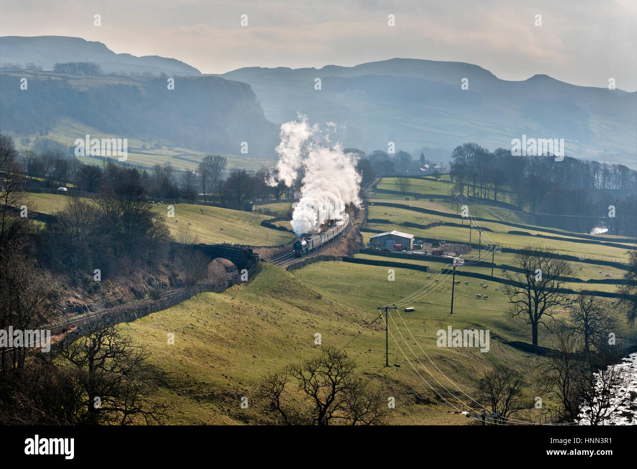Stainforth, North Yorkshire, UK. 15th February 2017. Steam locomotive Tornado hauls a train from Skipton to Appleby; seen here in Ribblesdale near Stainforth in the Yorkshire Dales National Park on 15th February 2017. This is; day two of this service; in a week that marks the first time a steam locomotive has hauled a scheduled train on the national railway network since steam was withdrawn from services in 1968. Credit: John Bentley/Alamy Live News Stock Photo
