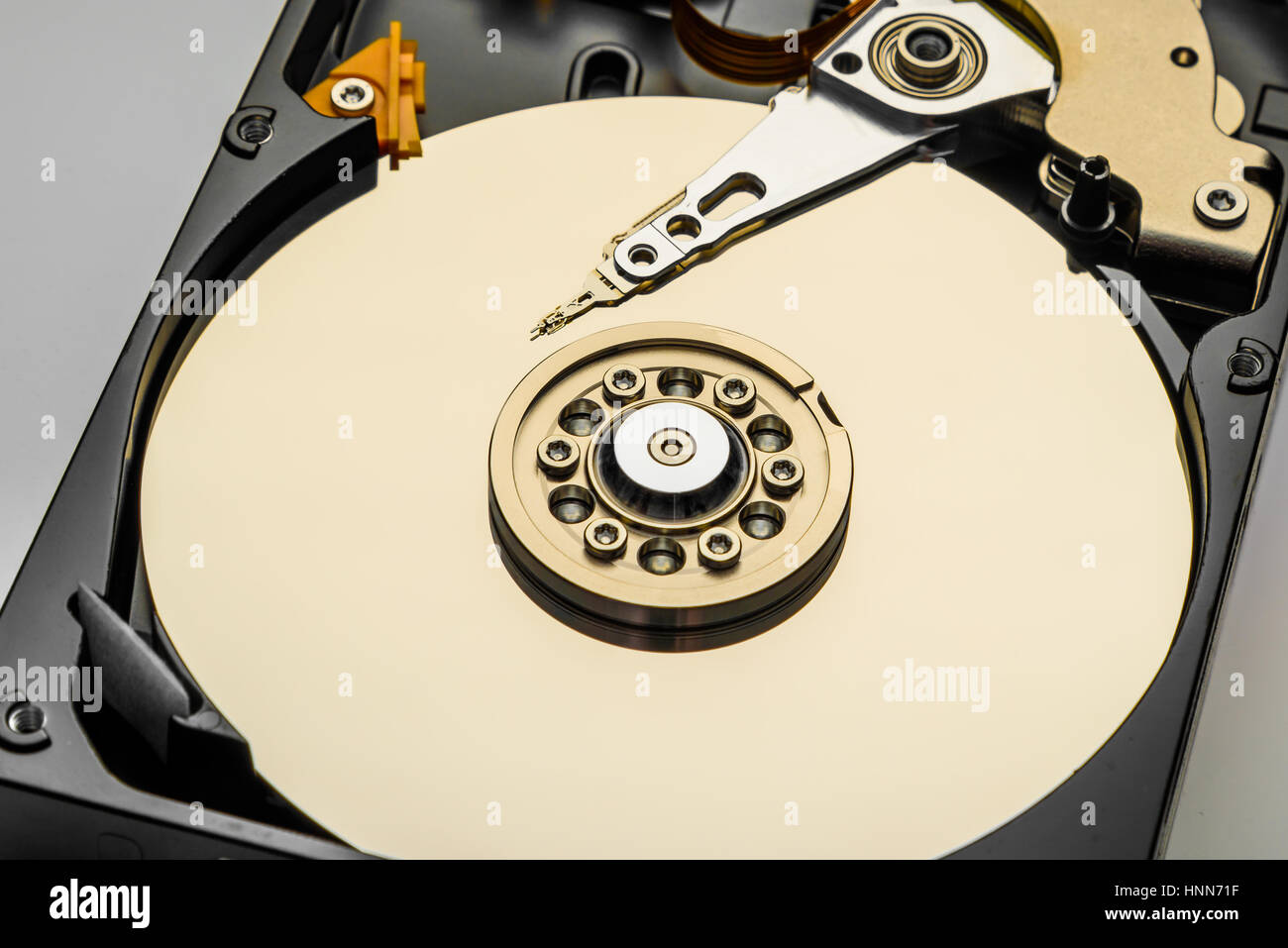 disassembled computer hard disk in gold color closeup isolated Stock Photo