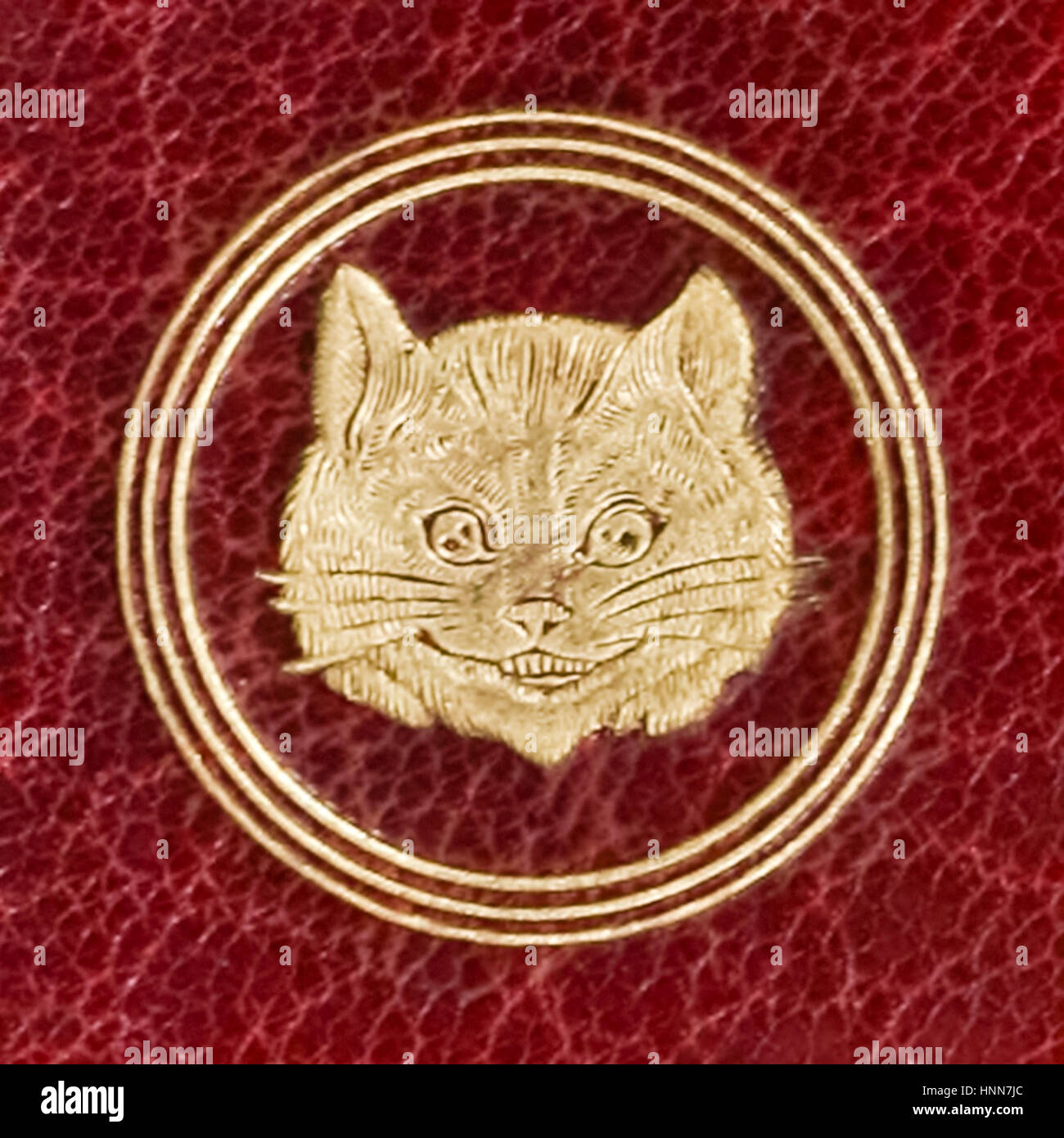 Close-up of the Cheshire Cat embossed on the back cover of a burgundy Morocco leather edition of ‘Alice’s Adventures in Wonderland’ by Lewis Carroll (1832-1898) published in 1865. Stock Photo