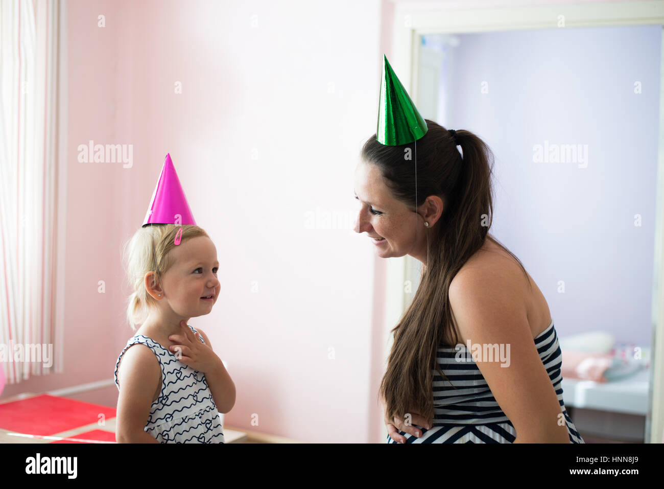 Beautiful mother with her cute daughter wearing party hats Stock Photo