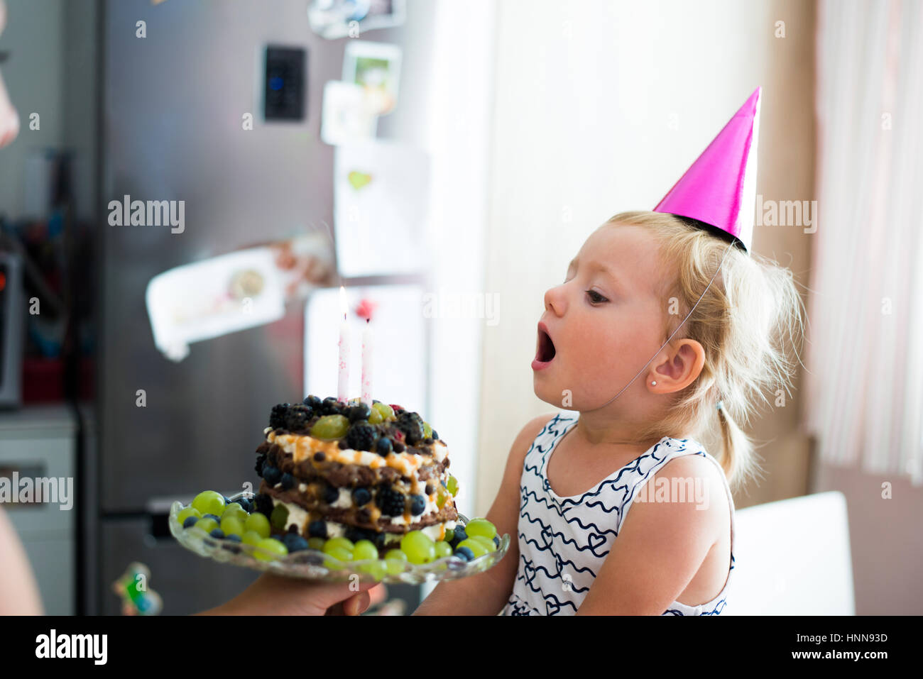 Cute little girl blowing candles on her birthday cake Stock Photo