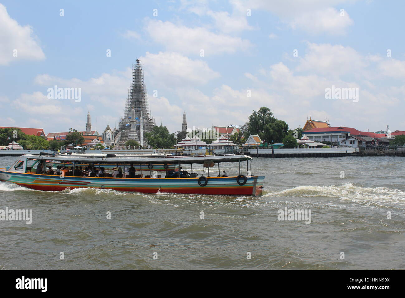 Public River transport on Chao Phraya river in Central Bangkok (Krung Thep) with pagoda in the background Stock Photo