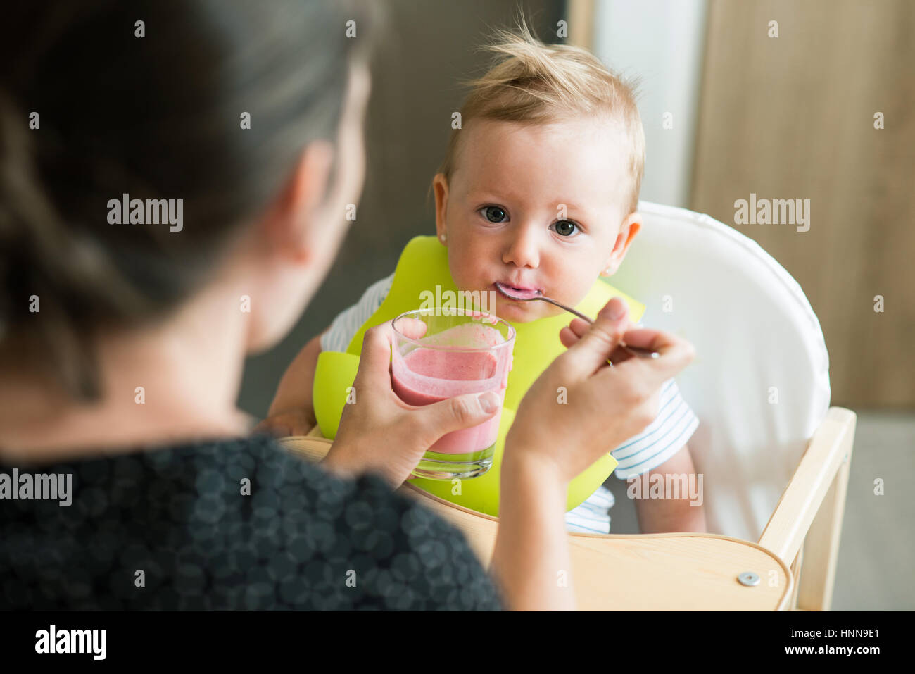 Unrecognizable mother feeding her baby daughter with yogurt Stock Photo