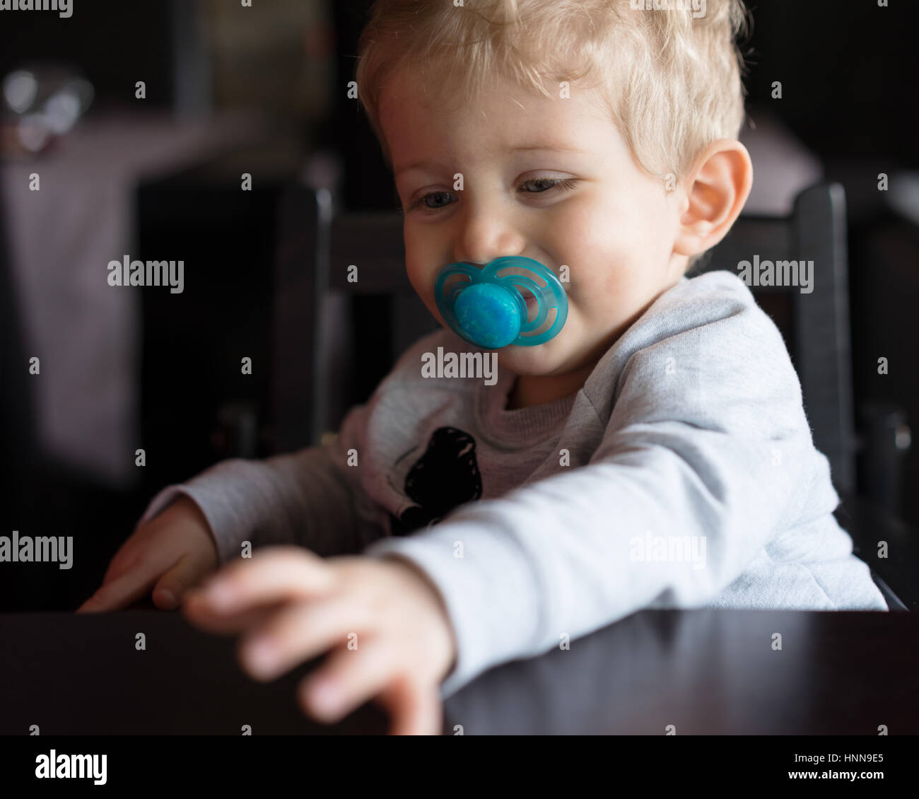 Baby boy sitting in high chair and smiling with pacifier at chinese ...