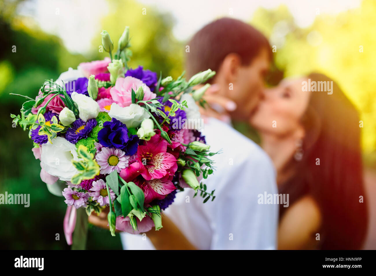 Bride holding a bridal bouquet and kissing of groom Stock Photo