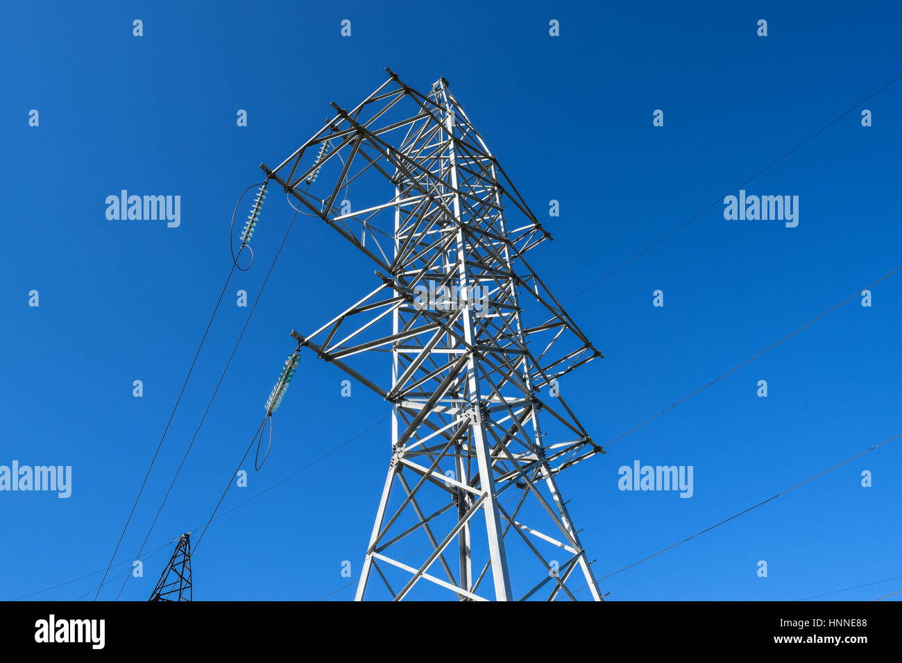 Supports high-voltage power lines against the blue sky Stock Photo - Alamy