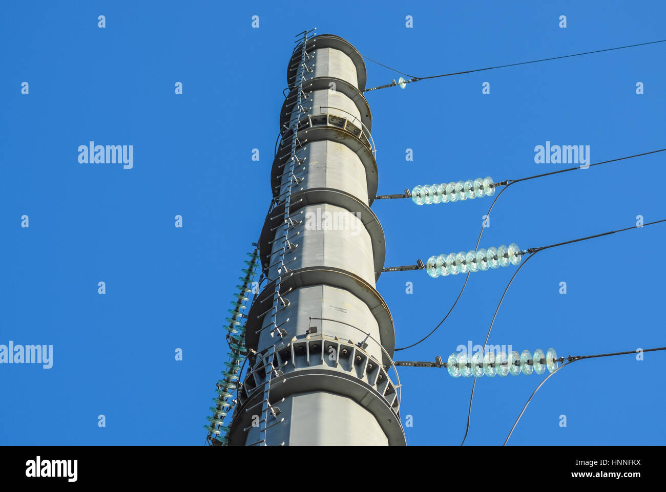 Supports high-voltage power lines against the blue sky Stock Photo - Alamy