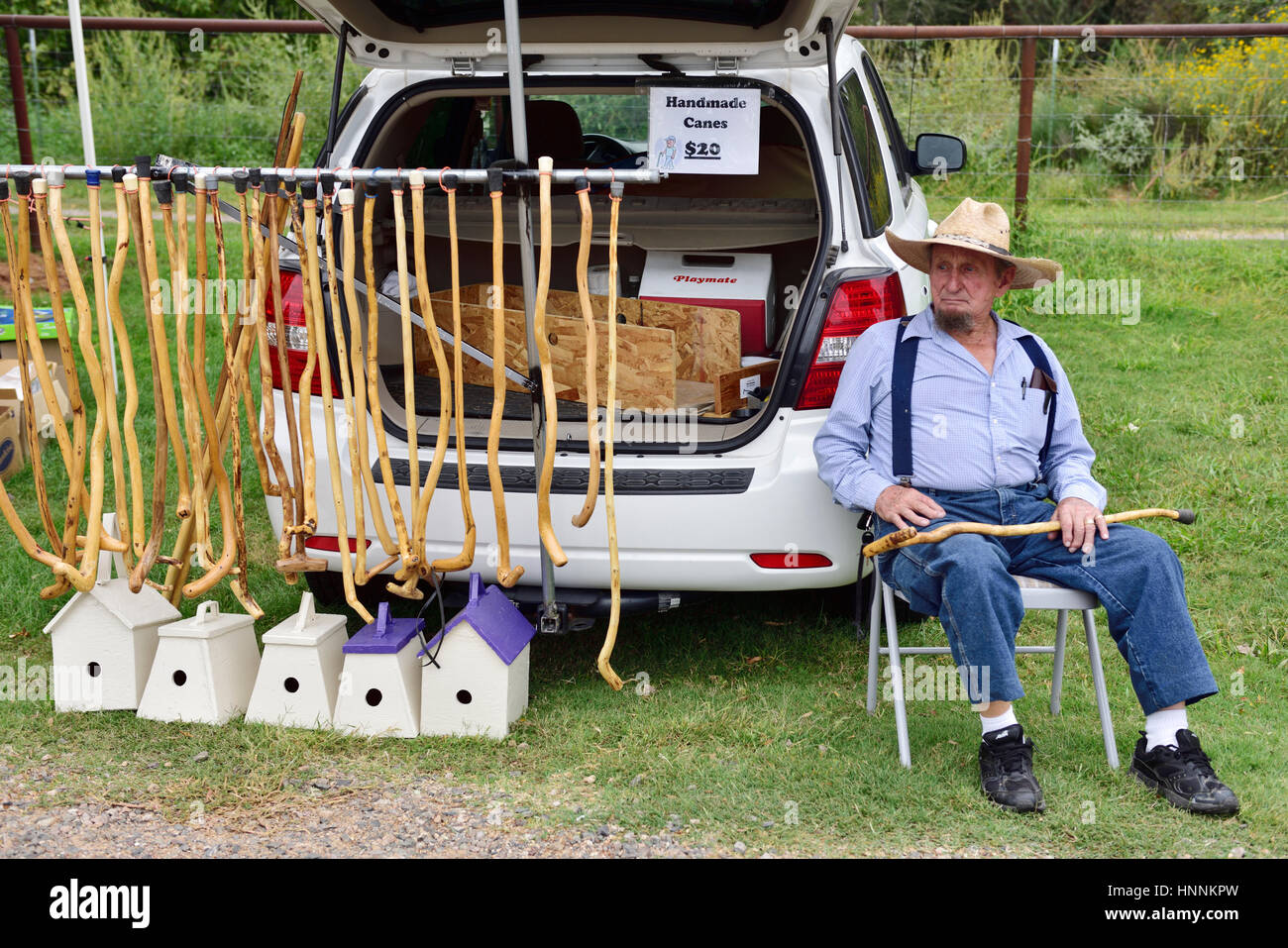 Man displaying and selling his handmade walking canes in local farmers market, Cornville, Arizona Stock Photo