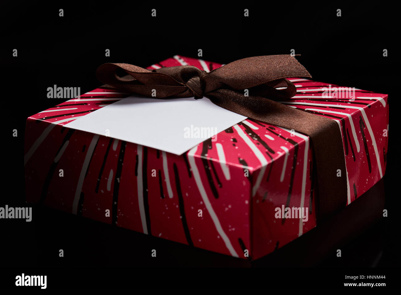 colorful gift red box with ribbon with paper label isolated on black background. Red christmas gift box isolated Stock Photo