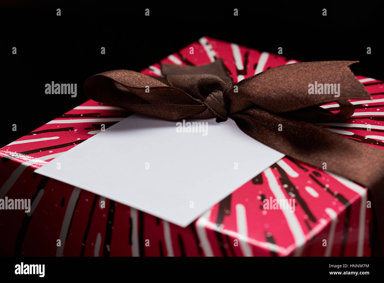 Close up of empty paper tag on gift colorful box isolated on black background Stock Photo