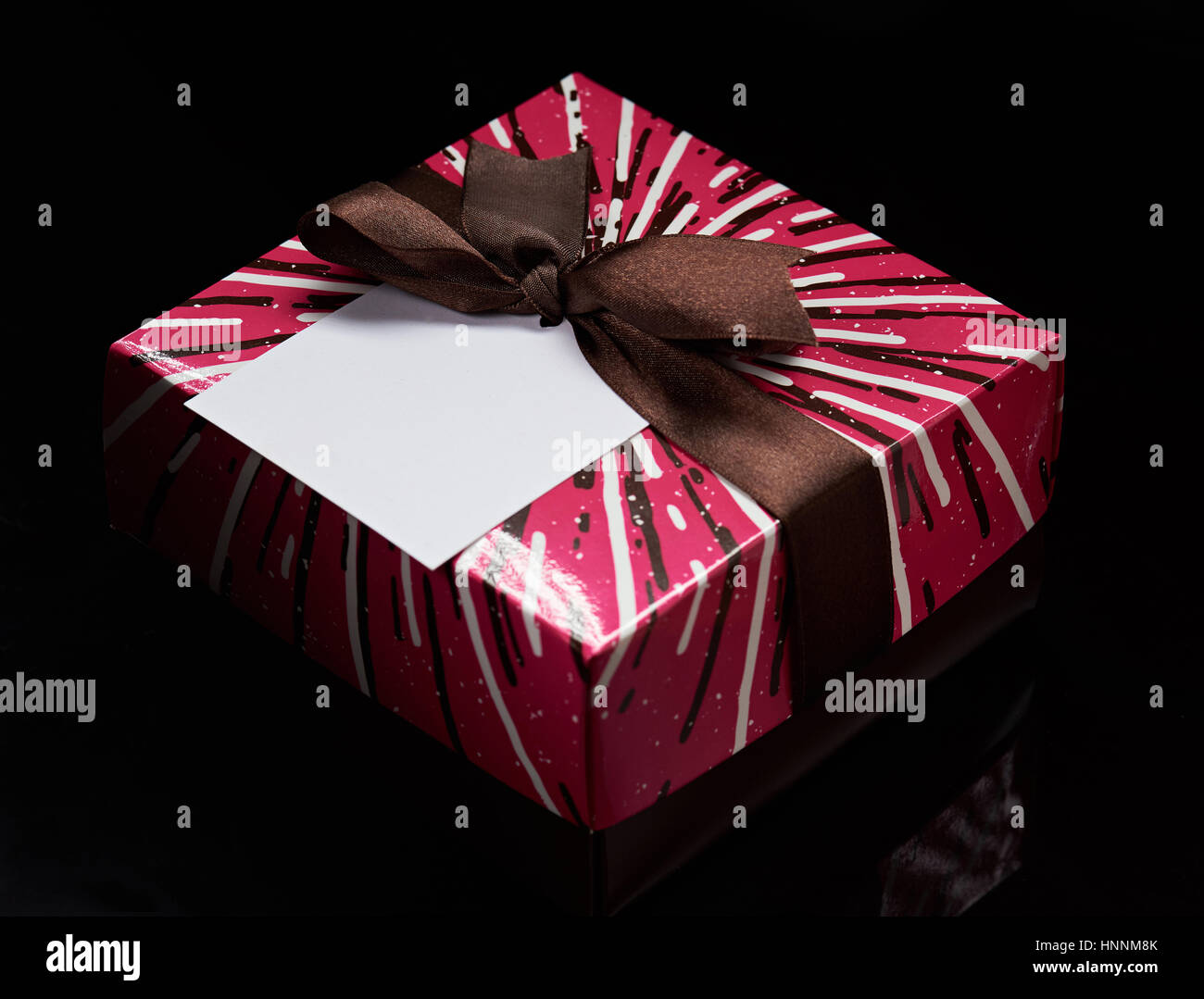colorful box with ribbon and empty tag isolated on black background Stock Photo
